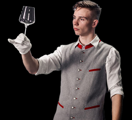 Ein konzentrierter Junge in Berufskleidung hält ein Weinglas.