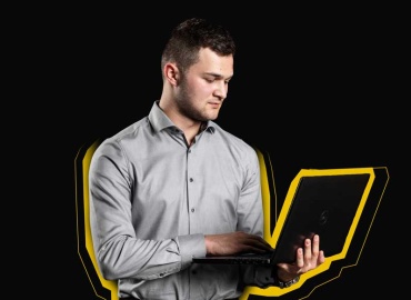 Ein junger Mann mit einem Laptop in der Hand.